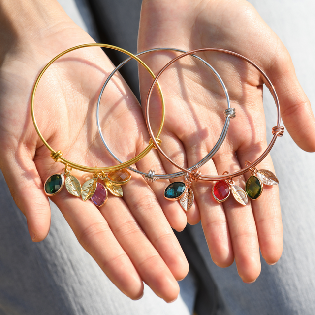 gold, silver, and rose gold Personalized Birthstone Initial Bracelets on model's palms