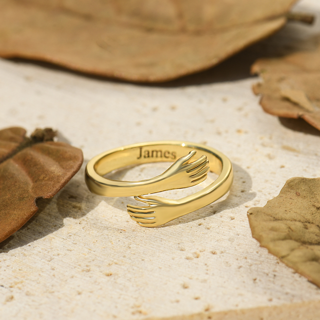 gold Custom Hug Ring on sand surrounded by leaves