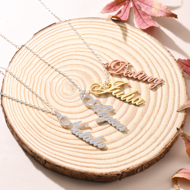 the vertical name necklaces - silver, gold, rose gold on top of a piece of wood