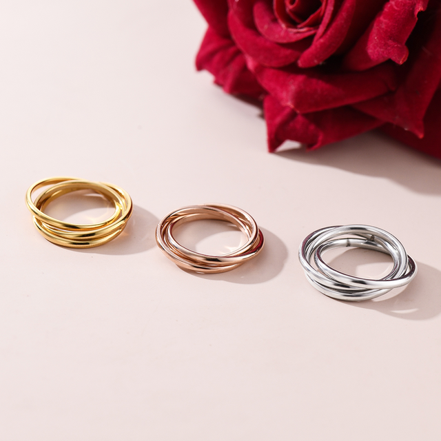 gold, rose gold, and silver Dainty Interlocking Fidget Rings on plain canvas with red rose at the background