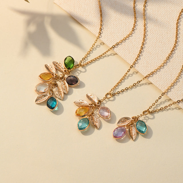 Dangling Birthstone Initial Necklaces on a plain canvas