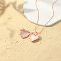 an opened rose gold Engraved Heart Locket Necklace on sand with flat white stone
