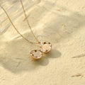 an opened gold Round Ball Locket Necklace on sand