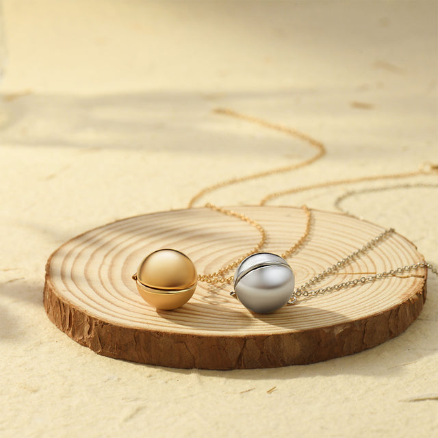 gold and silver Round Ball Locket Necklaces on a piece of wood