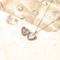 an opened silver Stone Heart Locket Necklace on sand with transparent crystals