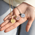 gold, silver, and rose gold Monogram Script Birthstone Necklaces on model's palm