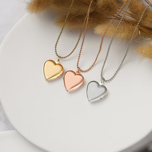 gold, rose gold, and silver Minimalist Heart Locket Necklaces on white disc and leaves