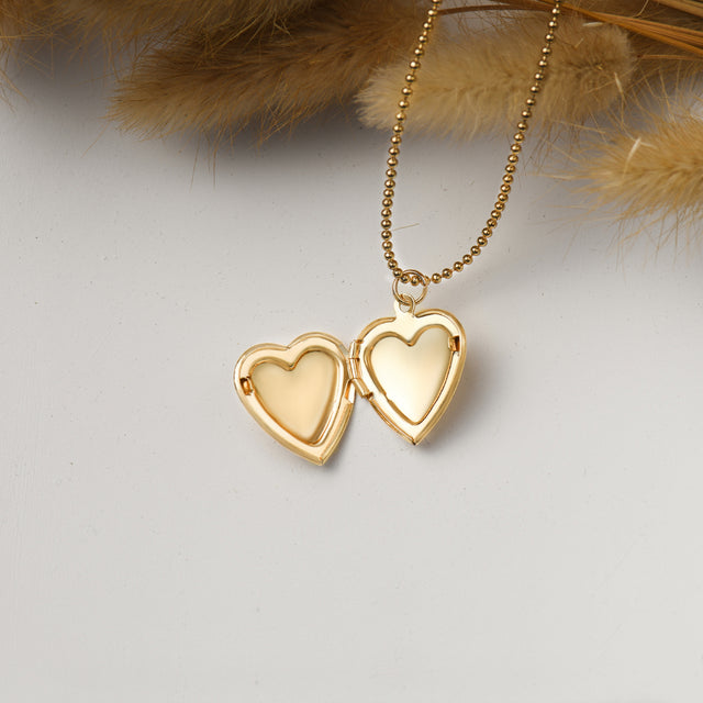 an opened gold Minimalist Heart Locket Necklace on white disc