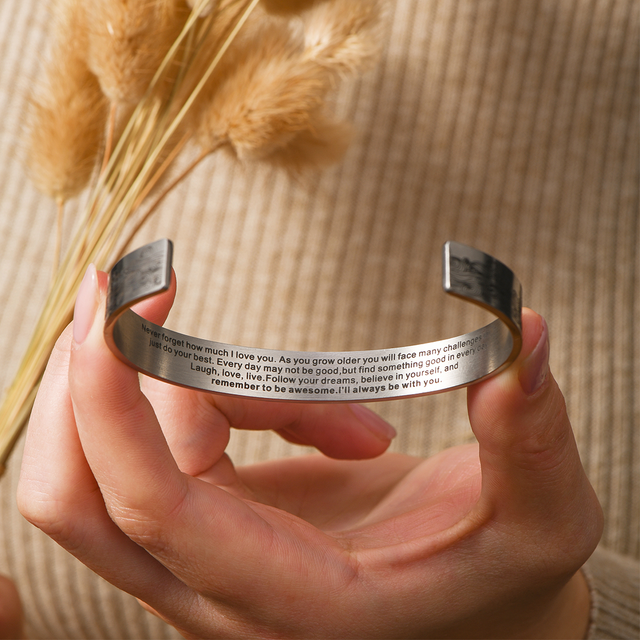 model holding the cuff bracelet showcasing the engraved text inside