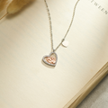 Baby Feet Heart Pendant Necklace on a book page