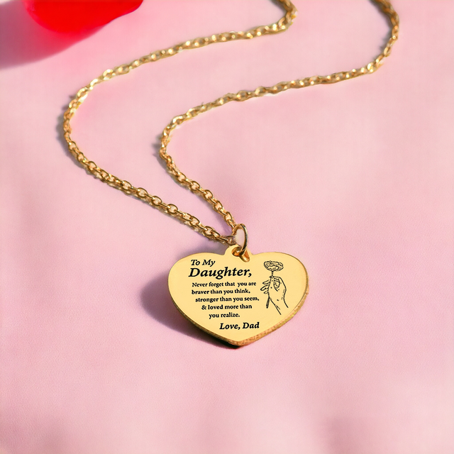 gold engraved heart necklace on plain pink canvas