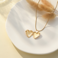 an opened gold Dainty Heart Locket Necklace on top of a clean white disc