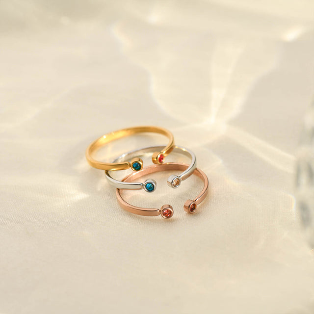 gold, silver, and rose gold Dual Birthstone Rings stack together on a clear canvas