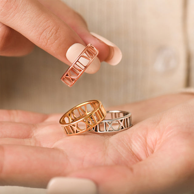 rose gold, gold, and silver variants Personalized Roman Numerals Rings on model's palm