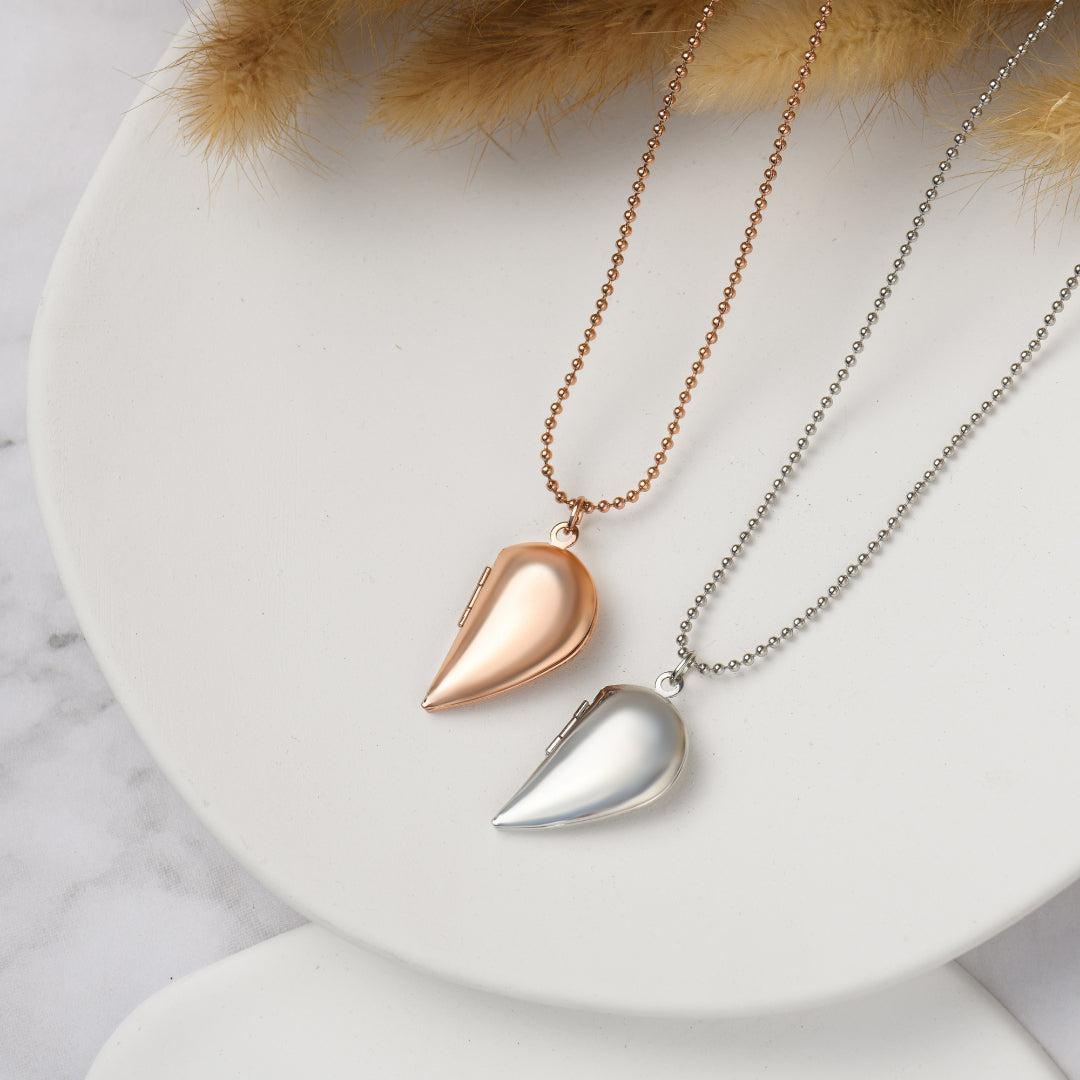 rose gold and silver colored Couple's Heart Locket Necklaces on a white circle disc